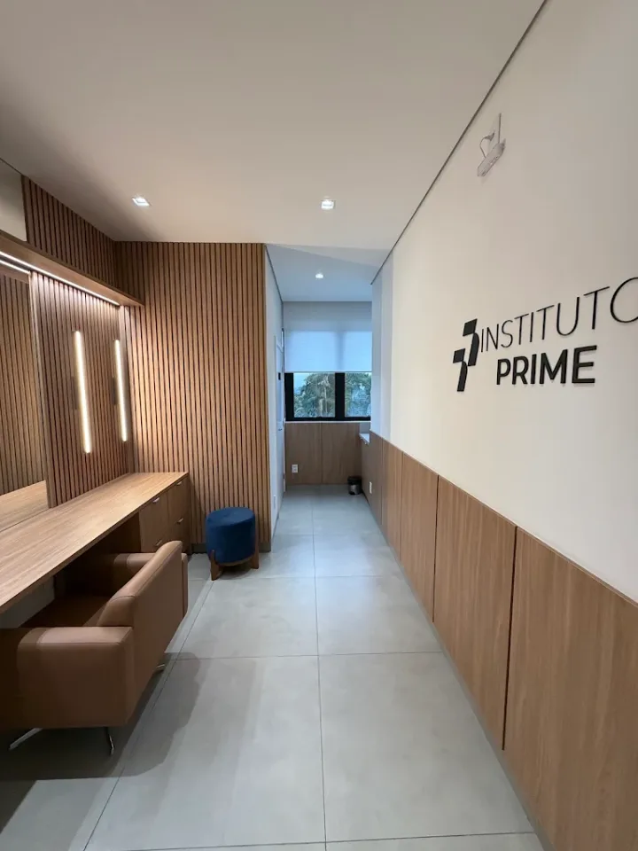 Recepção do Instituto Prime, com painel de madeira, poltronas e a marca na parede